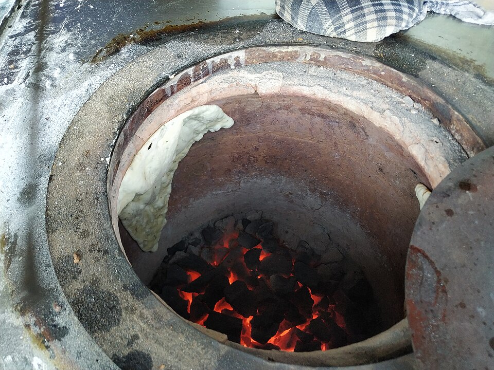 Bread baking against the wall of a charcoal-fired tandoor